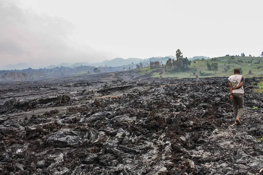 Volcanologists walk across hardened lava in Goma.