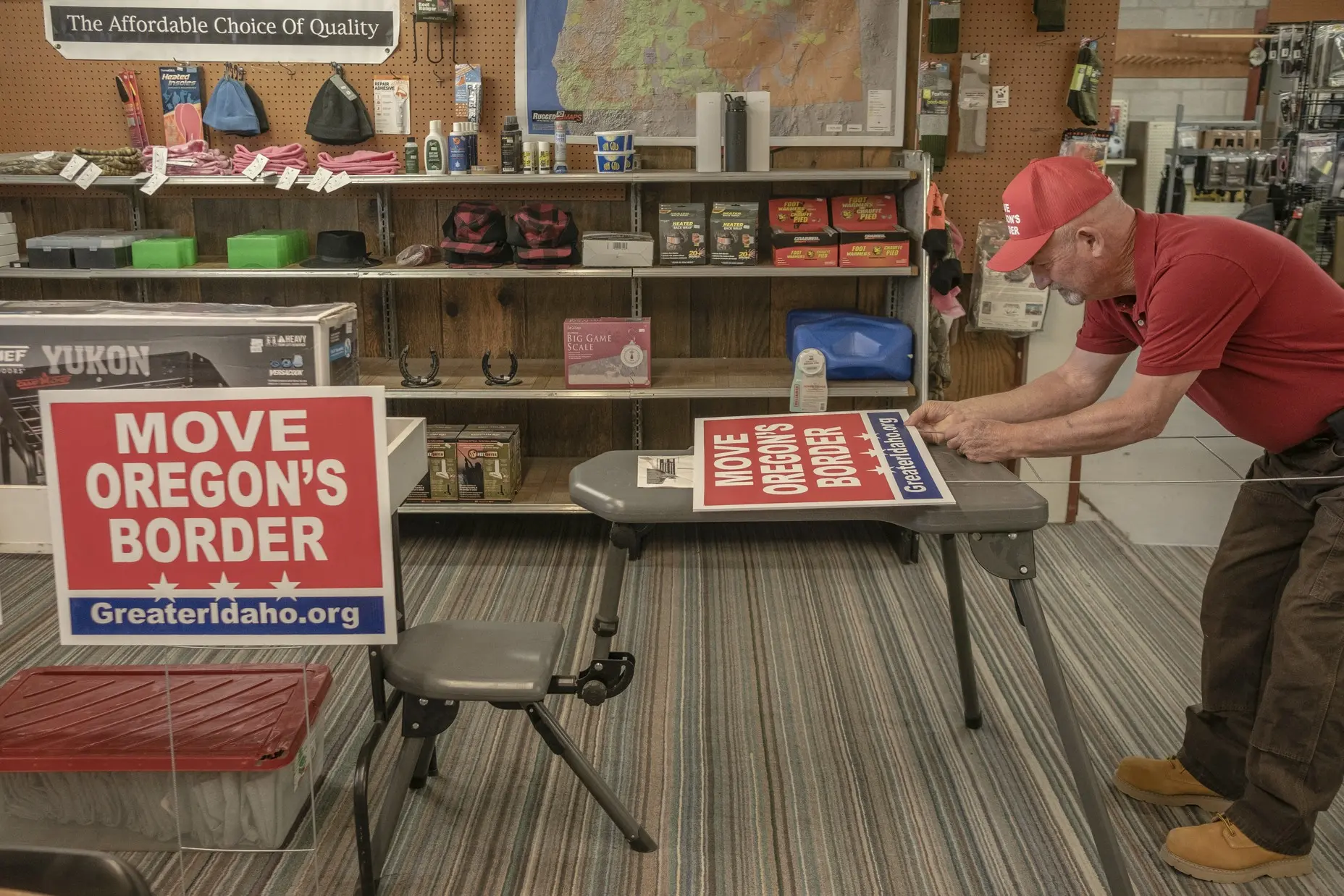 Man prepares a Move Oregon's Border yard sign inside a shop