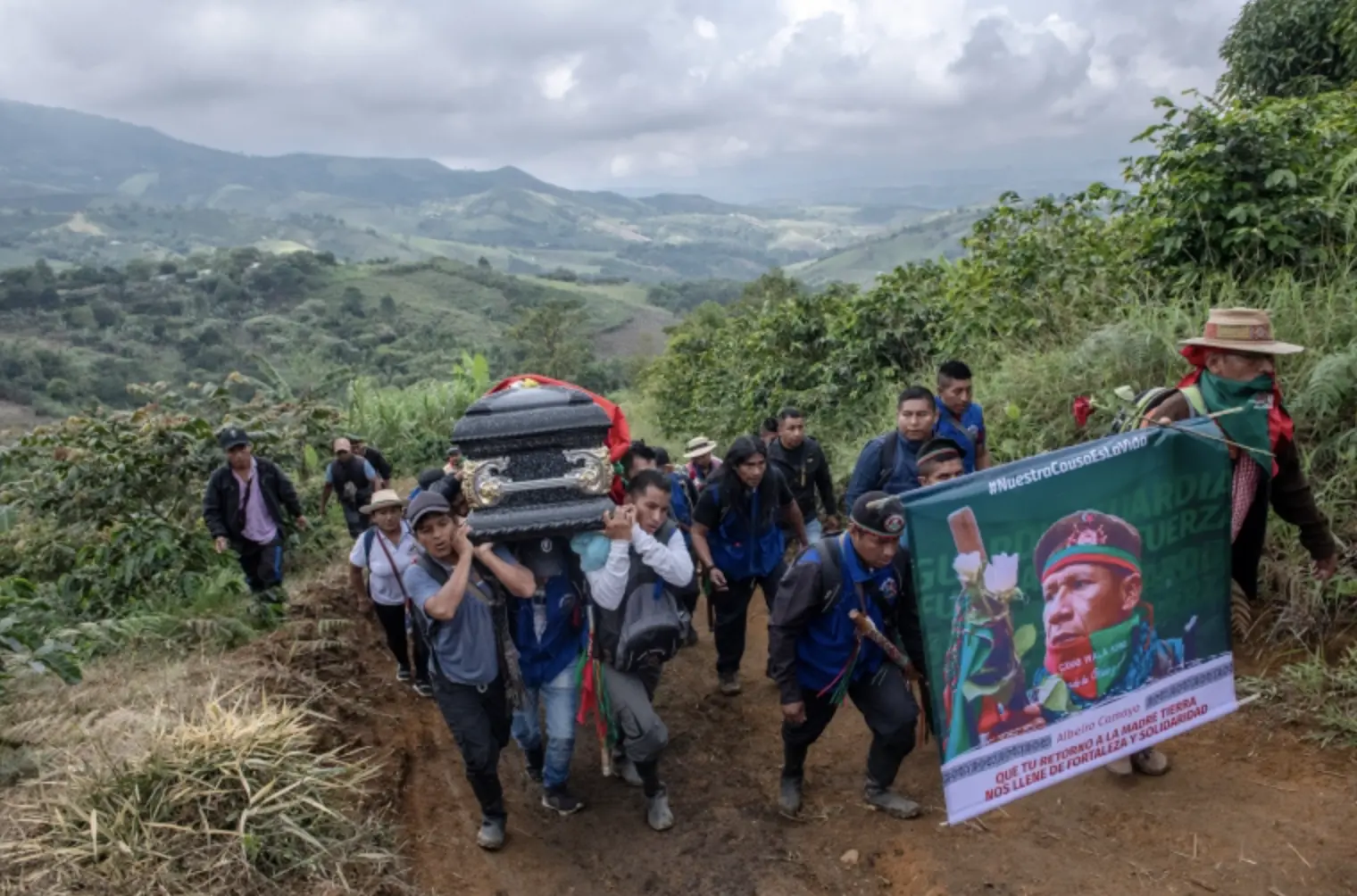 Indigenous family members carry coffin up on the hill 