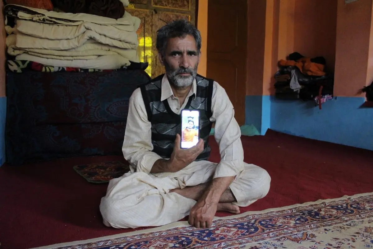 father holds phone with photo of son