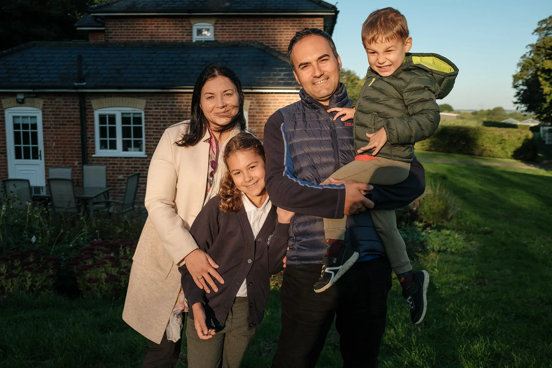 Family poses for photo outside of home