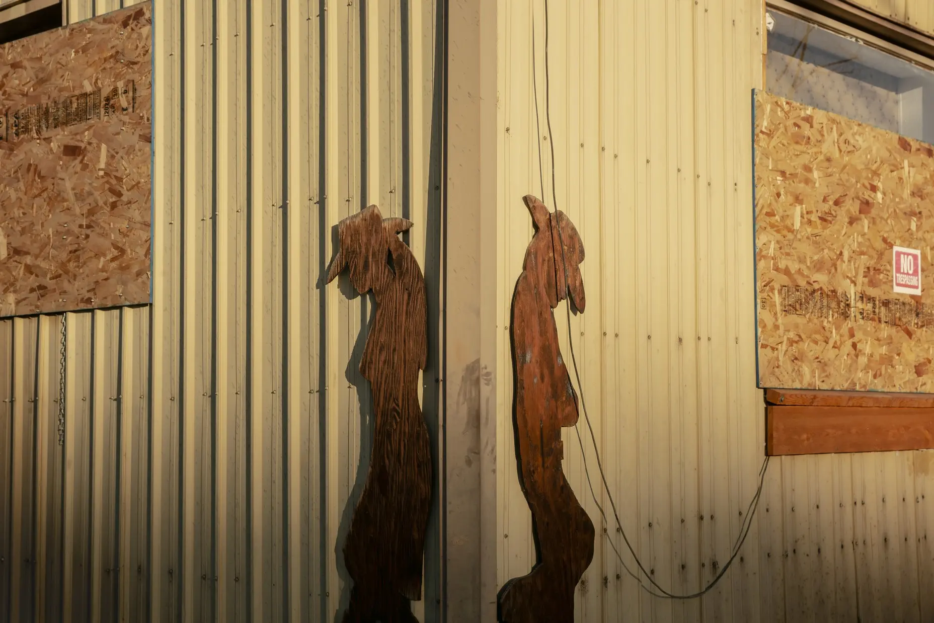 Cowboy wood figures cut from plywood are nailed to a boarded up building in Hines, Oregon