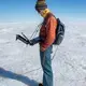Student Aidan Stansberry collects data to help map the ice sheet bed. Image by Amy Martin. Greenland, 2018. 
