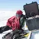 The 24-hour sunlight is so bright that researcher Toby Meierbachtol had to make a tent over his head in order to see the screen of a computer they're using to log the data from the ice sheet bed. Image by Amy Martin. Greenland, 2018. 