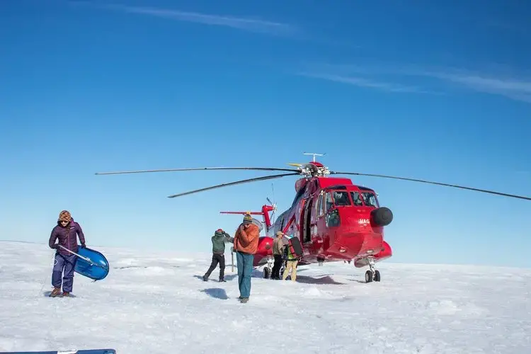 A team of three professors and three students unload the helicopter at their research site on the Greenland ice sheet. Image by Amy Martin. Greenland, 2018. 