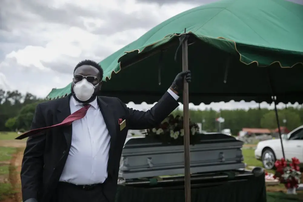 Cordarial O. Holloway wears a protective mask as his tie blows in the wind after a funeral at Cedar Hill Cemetery, on Saturday, April 18, 2020, in Dawson, Ga. Image by Brynn Anderson / AP Photo. United States, 2020.