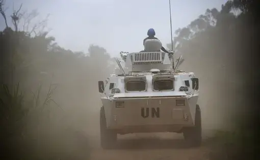 An armored UN personnel carrier on patrol drives down a road.
