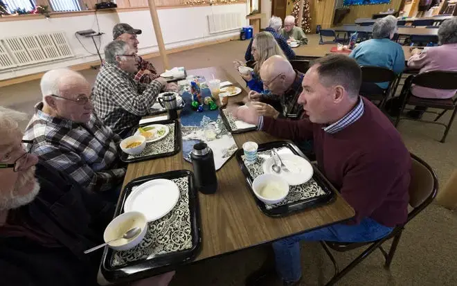 Dairy farmer Randy Roecker, right, talks with retired dairy farmer Hank Elfers, second from left, at St. Peter's Lutheran Church in Loganville. Roecker helped organize 'Farm Neighbors Care' events to help farmers who need support. Image by Mark Hoffman. United States, 2020. 