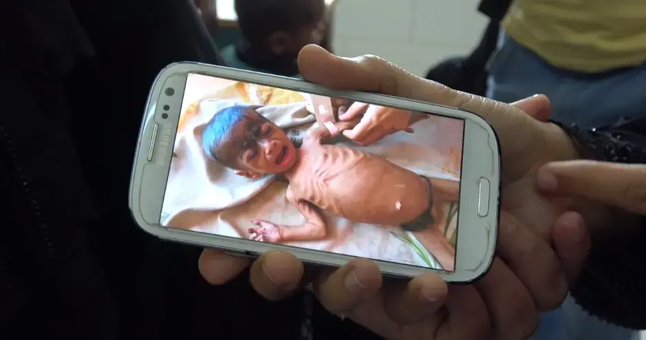 A screen capture from a video of 8-month-old Fadl Halabi is shown on a smartphone. (AP Video/Maad Alzekri) 