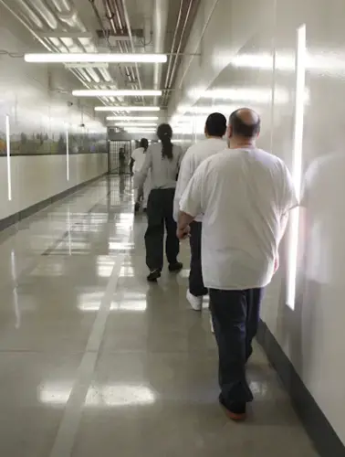 Inmates walk down a hallway at the Idaho State Correctional Center, a prison south of Boise that used to be known as the 'gladiator school' because of the violence that occurred there. Image by Madelyn Beck / Boise State Public Radio. United States, 2020.