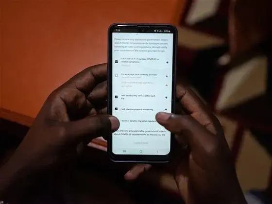 Uber driver Emmanuel Bitok, one of more than 80 drivers who spoke with NBC News, confirms the safety requirements on the Uber app before heading out for the day. Image by Nichole Sobecki/NBC News. Kenya, 2020.<br />
