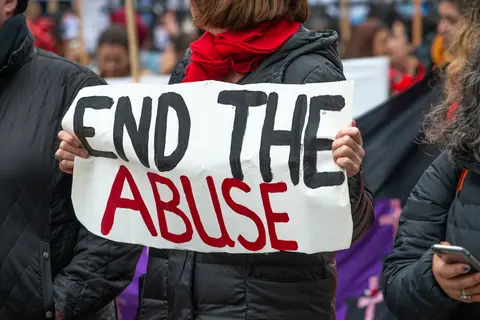 A protester holds a banner reading, "End The Abuse" at a demonstration in London.