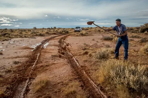 Paul Denetdeal weilding a shovel. Seventy-seven percent of reservation roads are unmaintained dirt roads. Image by Mary F. Calvert. United States, 2020.