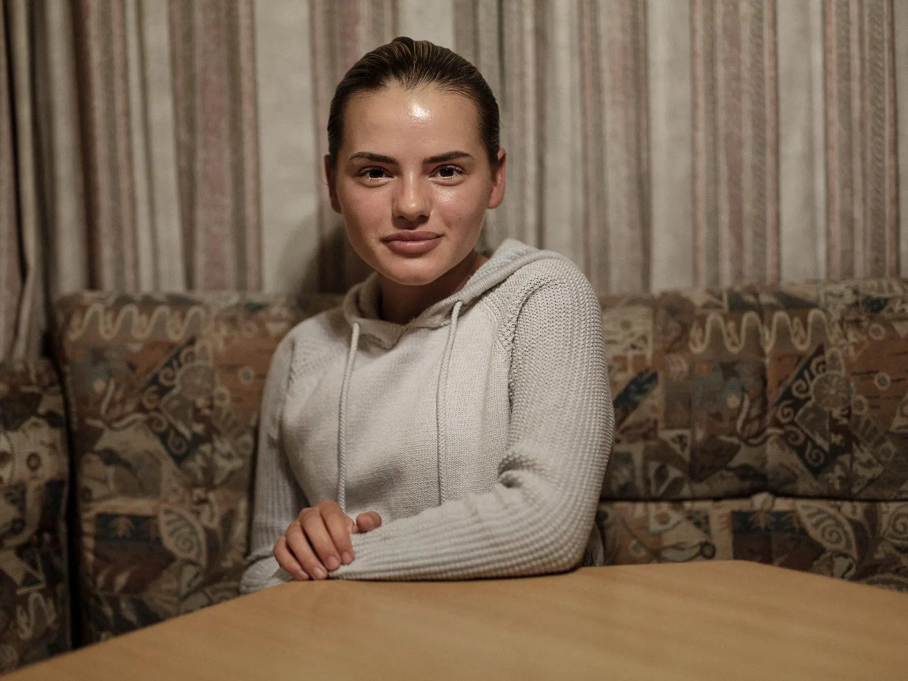Young woman wearing a sweater sits at table inside her camper 