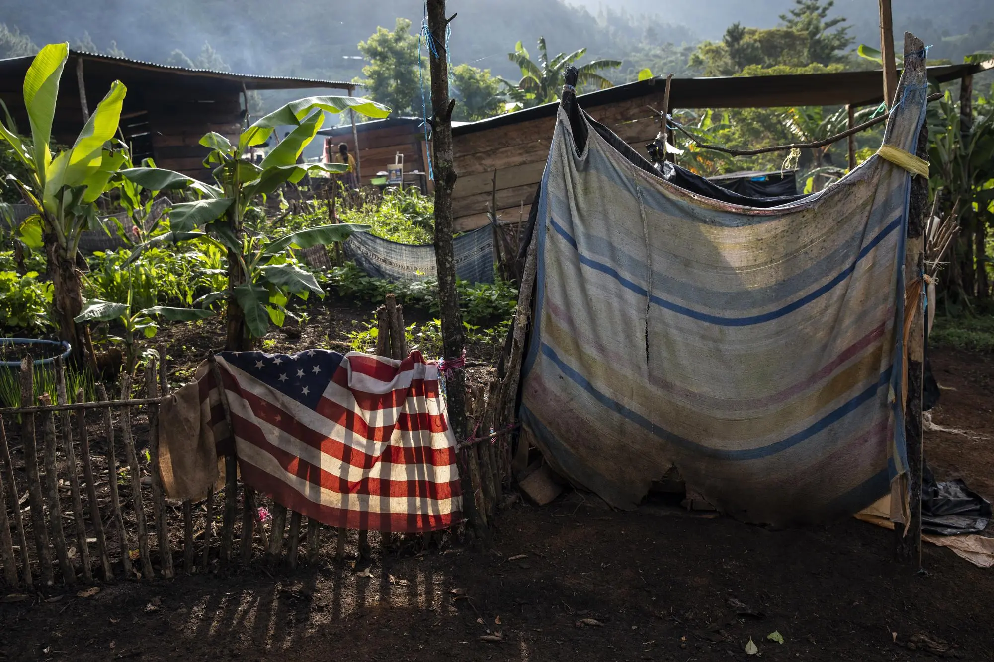 Donations including a US flag hang over a fence of a makeshift house 