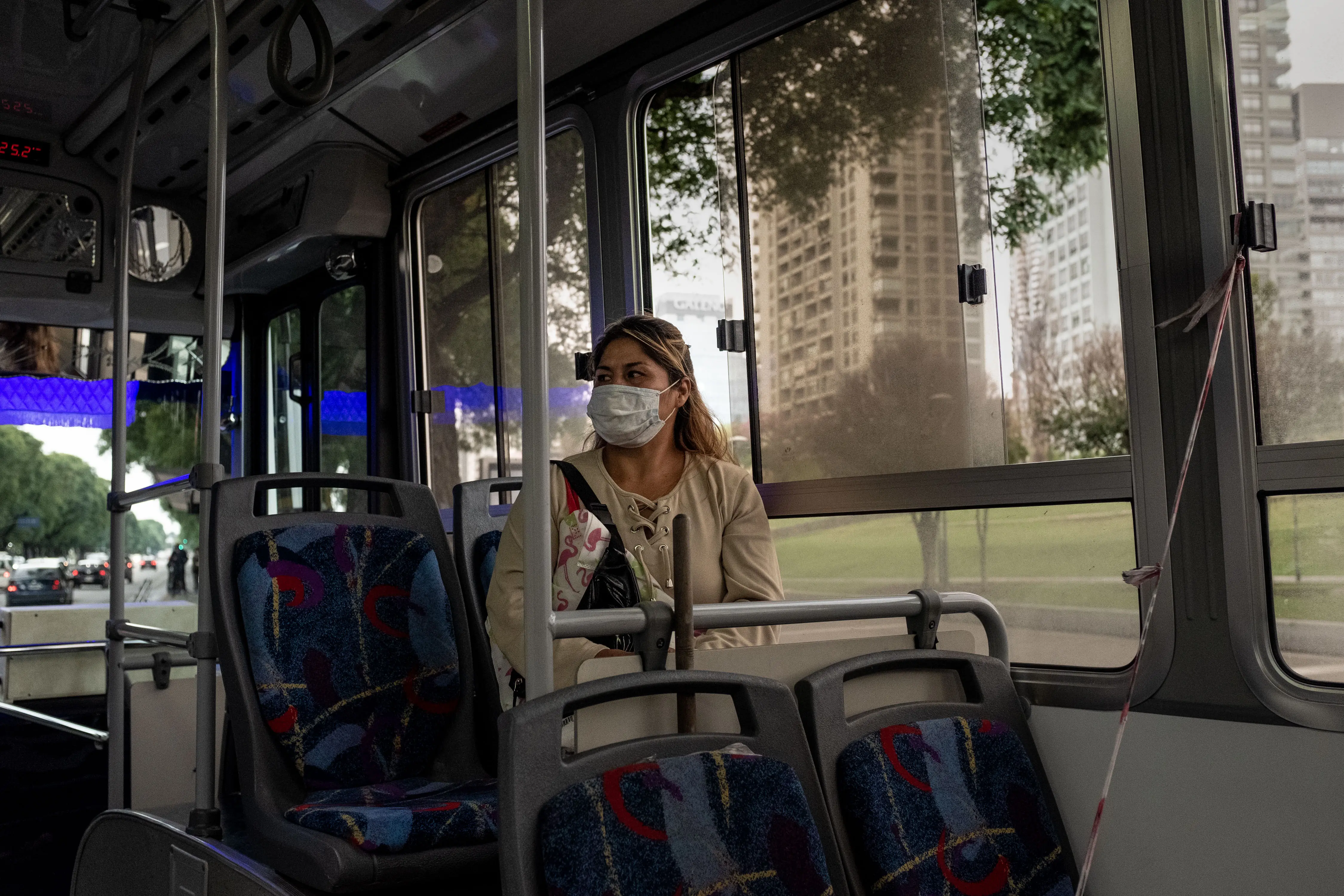 A person wearing a medical face mask sits in a bus.