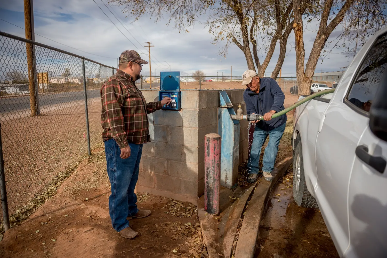 Leroy Canyon and Brandon Canyon are pictured getting getting water from tanks in Tuba City. Image by Mary F. Calvert. United States, 2020.