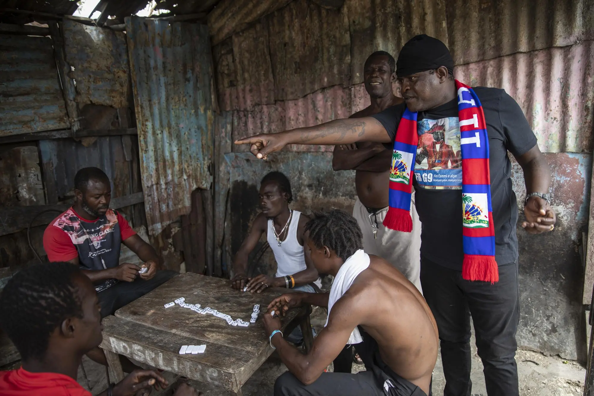 Gang members talk over a game of dominos 
