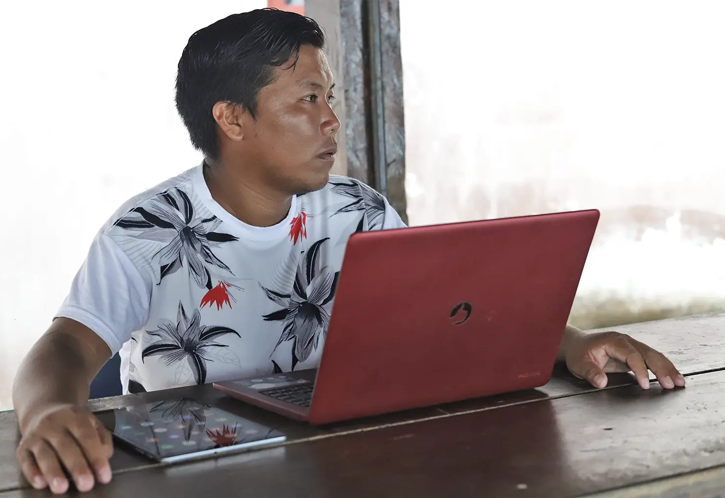 Indigenous man sits in front of laptop