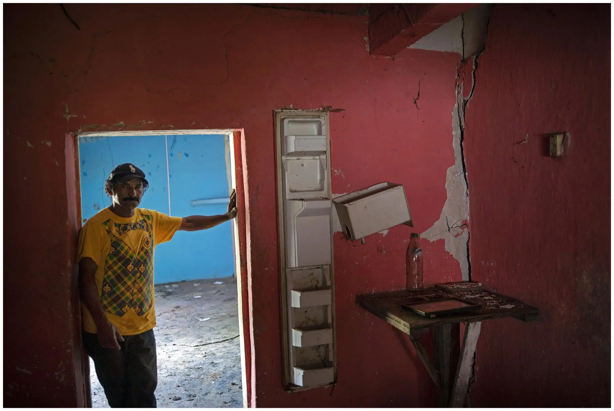 man stands in his damaged home