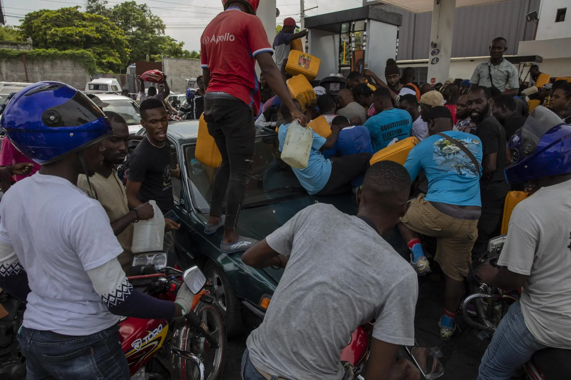 People rush to fill gas at a station in Haiti