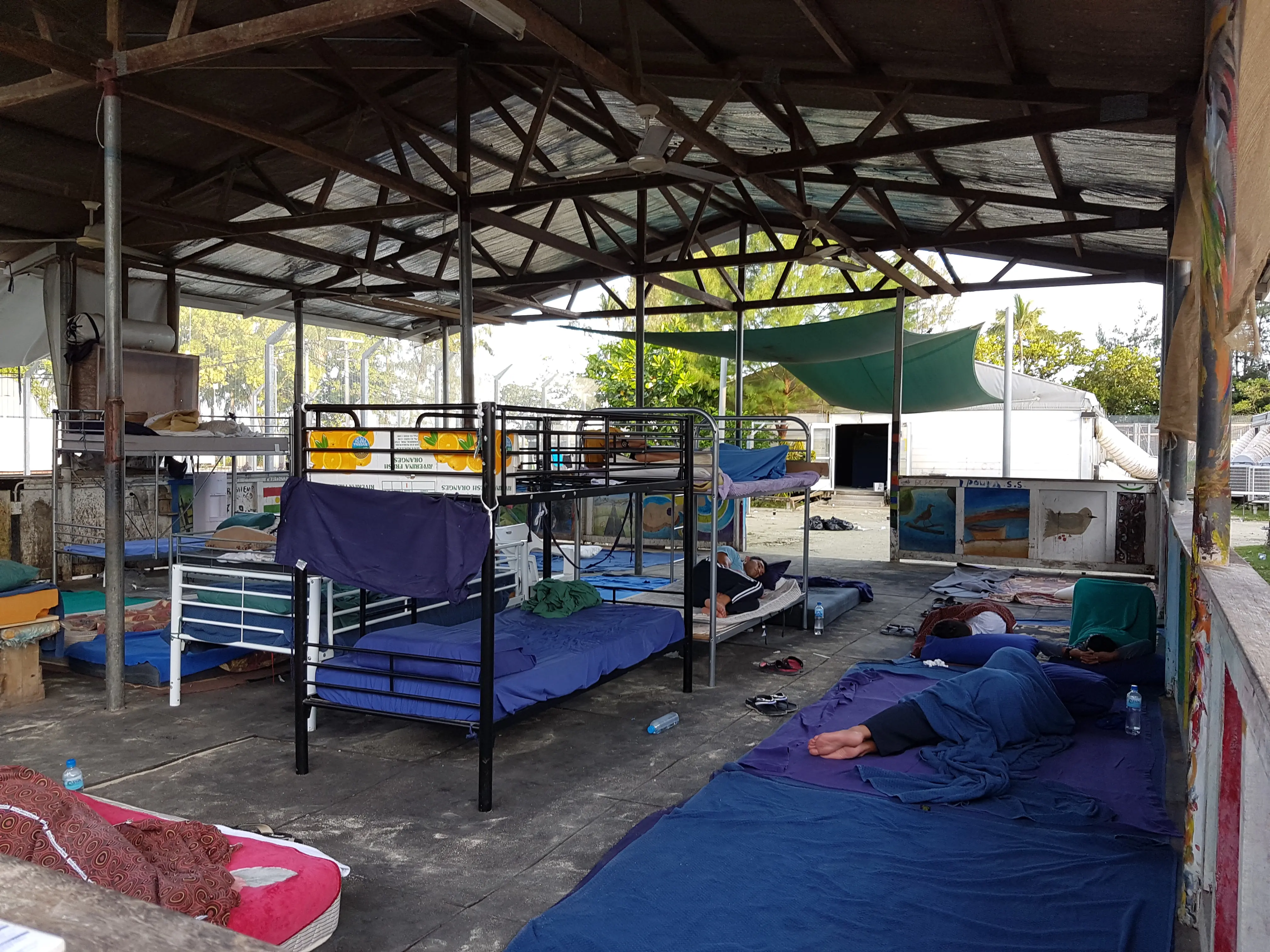 Refugees sleep outside on the ground and in bunk beds