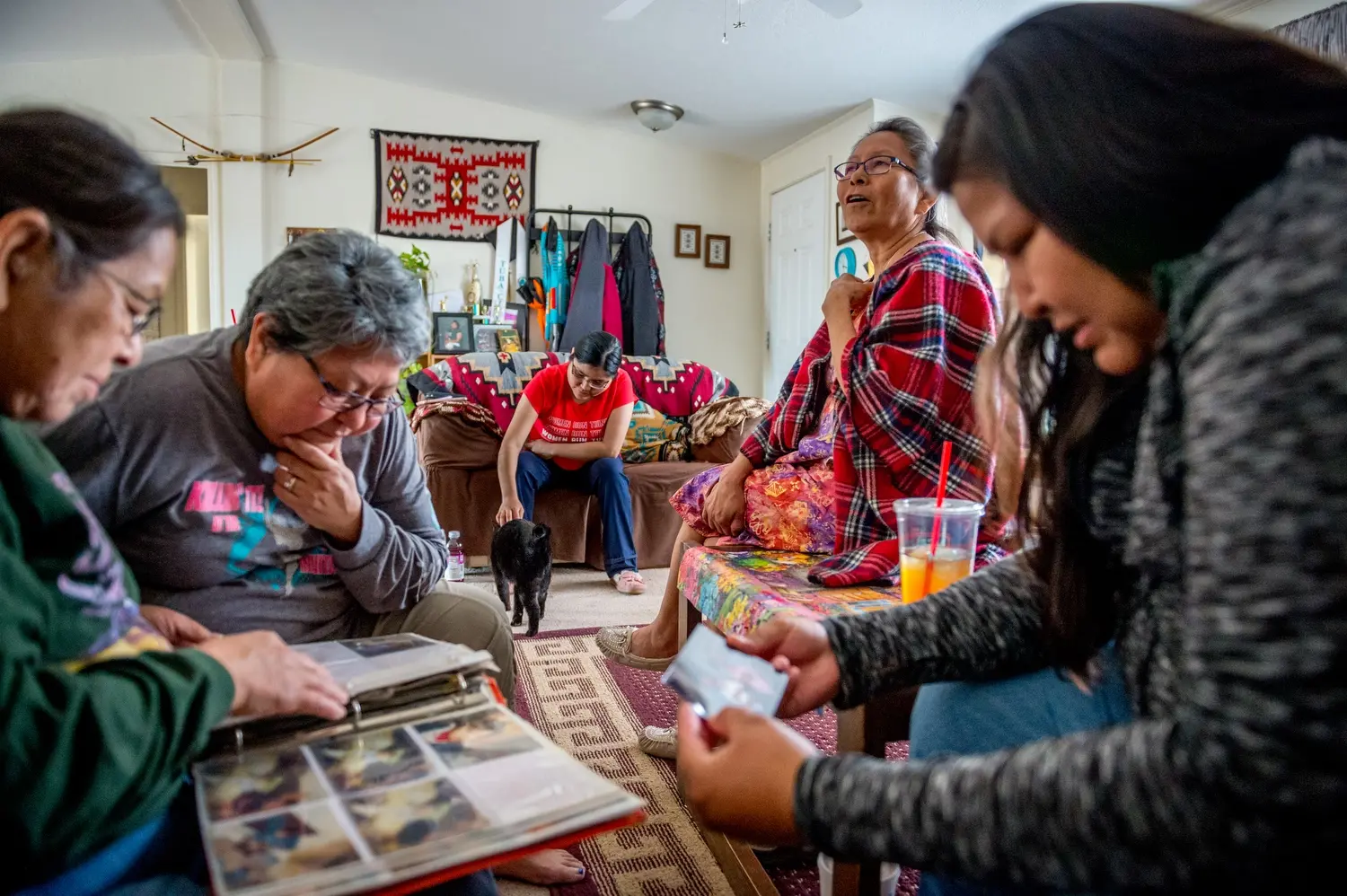 Linda Talker, Leona Begishie, Tara Begay and Carol Talker look at family photo albums at their home in Cameron, Ariz. Image by Mary F. Calvert. United States, 2020.