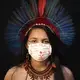 Samela, 23, of the Sateré Mawé indigenous ethnic group, poses for a portrait wearing the traditional dress of her tribe and a face mask amid the spread of the new coronavirus in Manaus, Brazil, Wednesday, May 27, 2020. Samela, whose mother Sonia Vilacio recovered from symptoms consistent with COVID-19 using natural remedies at home, is the first member of her family to attend university, where she studies biology. Image by Felipe Dana / AP Photo. Brazil, 2020.